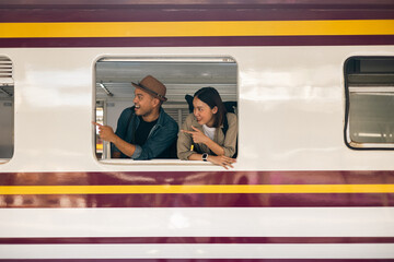 Couple asian traveller with bag on honeymoon travel by train Sticking head outta the window. Happy...