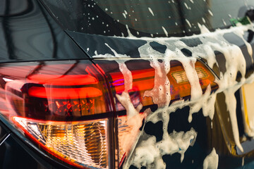 Foamy cleansing foam. Soap bubbles on body of the car. Service. Car wash cleaning station....