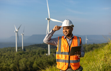 Engineer India man working with tablet at windmill farm Generating electricity clean energy. Wind...