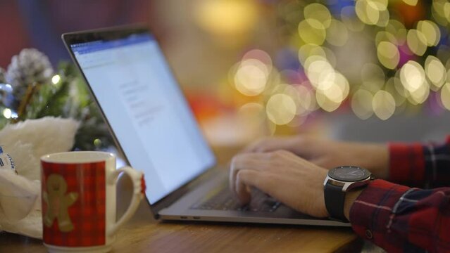 Close up of man�s hands working on computer in beautefully decorated room for Christmas. Slow motion. 
