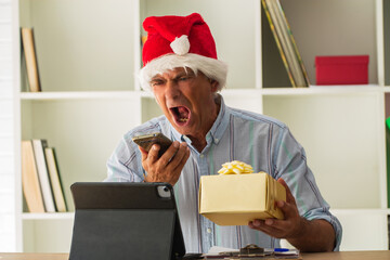 man with santa claus hat in the office shouting and angry with the phone
