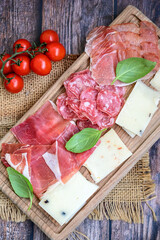 Slices Of  Traditional Italian antipasti mortadella Bolognese,salame Milano, parmesan cheese  and prosciutto crudo   on a wooden  cutting board.
