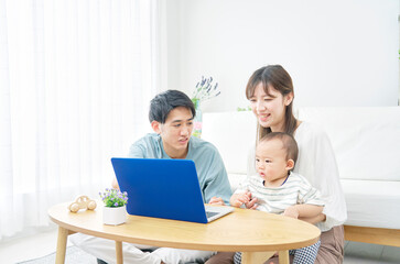 Fototapeta na wymiar 家で赤ちゃんとパソコンを見る両親