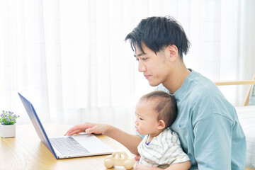 Fototapeta na wymiar 家で赤ちゃんとパソコンを見る父親
