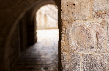Obraz premium Blurred pedestrian arched tunnel in Old City of Jerusalem, in front of Jerusalem stone column. Israel.