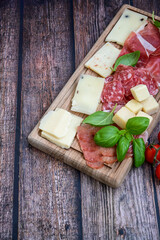Slices Of  Traditional Italian antipasti mortadella Bolognese,salame Milano, parmesan cheese  and prosciutto crudo   on a wooden  cutting board.