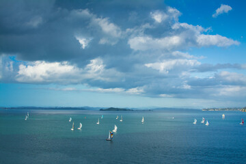 Fototapeta na wymiar Small sailing boats racing over calm waters of Auckland Harbour on a beautiful winter day. North Island, New Zealand