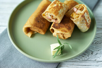 Pancakes with apples and a cube of butter on a green plate, close-up. A dish from a restaurant.