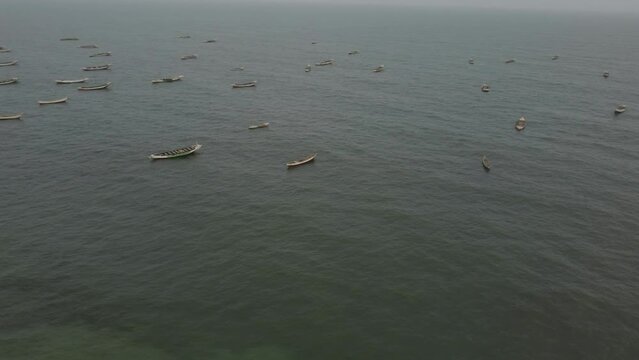 Rotating drone shot of the anchored fishing boats in Port Peche, Nouakchott, Mauritania. the shot shows finally the coast linr with the main building and the fishing boats standing on the beach
