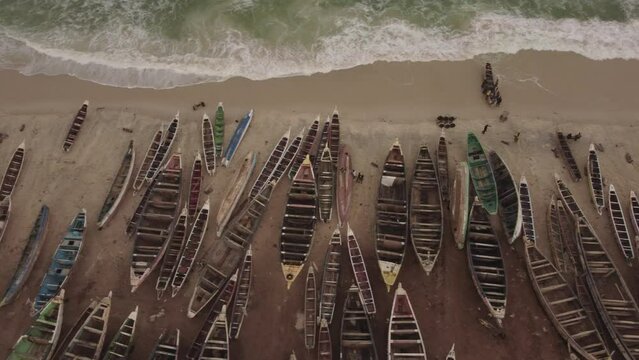 A drone zenith truck shot moving towards right along the coast line in the Nouakchott Port Peche, showing all the fishing boats standing on the sand.