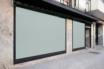 Front of a commercial premises with two white glass windows and faded marble walls and black painted steel edges and street are conventional flooring