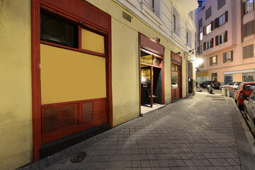 Facade of a local bar with a yellow facade and metal windows painted in red