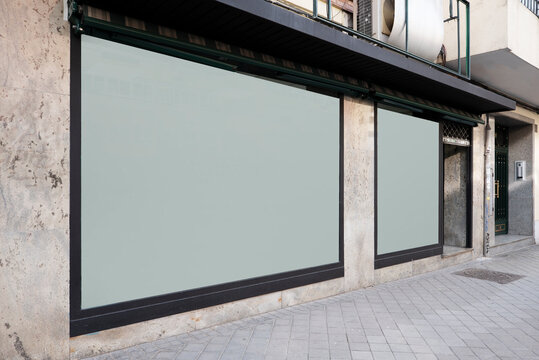 Front Of A Commercial Premises With Two White Glass Windows And Faded Marble Walls And Black Painted Steel Edges And Street Are Conventional Flooring