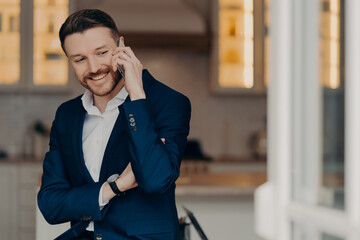 Happy executive director in stylish suit and with phone indoors