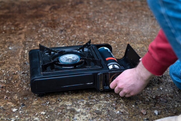 Active lifestyle. A man's hand turns on a portable gas stove. An alternative source for cooking at...