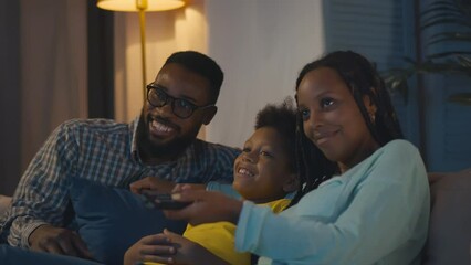 Delighted family sitting on sofa and watching movie on tv at home