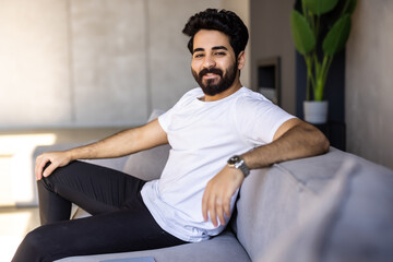 Fototapeta premium Split System. Satisfied Arab man sitting on couch in living room