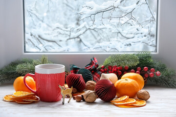 Festive Christmas decor on windowsill. tangerines, dried orange slices, nuts, cinnamon, deer toy,...