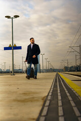 Young man walking down a train station with his suitcase in hand, he's going on a business trip