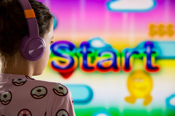 A child or teenager is playing computer video games on a large screen. Online video game technology and teen gaming addiction. Start on the screen