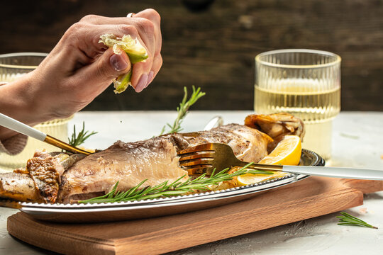 baked fish with lemon herbs and spices. two glasses of white wine, dinner concept. Restaurant menu, dieting, cookbook recipe top view