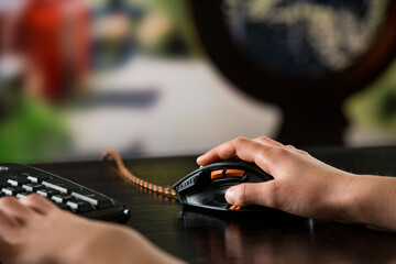 A child or teenager is playing computer video games on a large screen. Online video game technology and teen gaming addiction. Close-up child's hand with mouse