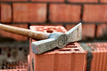 Construction tool for laying bricks and blocks. Bricklayer's tools - hammer, spatula, trowel, gloves. Hand tools on the background of brickwork.