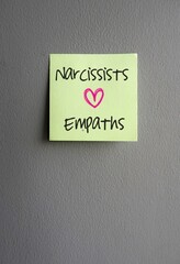 Note on gray background, with text NARCISSISTS and EMPATHS and love symbol, concept of two types of people are on opposite ends of the emotional care spectrum end up in relationships