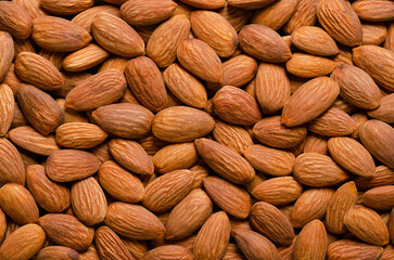 Shelled almonds, background from above. Raw, edible and whole dried nuts, botanically drupes, seeds and fruits of Prunus dulcis. Ready-to-eat as a snack, or used as an ingredient for baking. Photo.