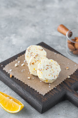 Salted butter with almonds and lemon zest, cut into circles, on a brown wooden board on a gray concrete background. Types of butter with additives for serving dishes.
