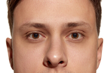 Closeup male brown eyes of young handsome man isolated on white studio background. Concept of men's health, vision, self-care, medicine and cosmetics.