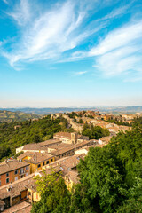 The view from above of the city, you can see the mountains and the roofs of the houses. Sun houses and tree tops seen from below.