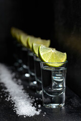 Fototapeta premium Tequila with lime and sea salt on a black table.