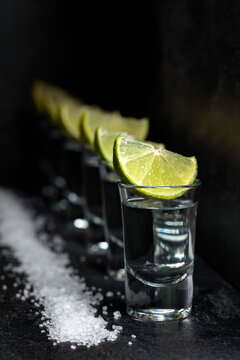 Tequila with lime and sea salt on a black table.