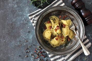 Homemade ravioli with potato and ricotts cheese served with crispy bacon. Top view with copy space. 