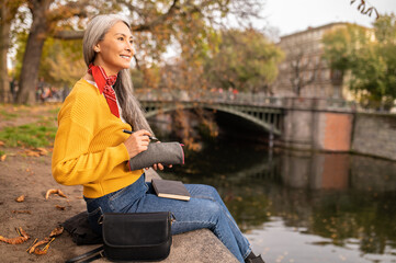 Woman sitting on the river bank and making notes