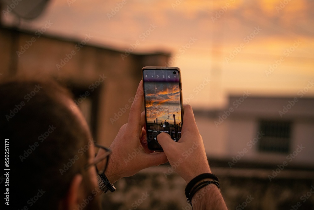 Canvas Prints Person taking a photo with a smartphone of the mesmerizing sunrise over the city