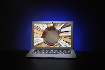 Many books on screen of modern laptop against dark background. Concept of electronic book