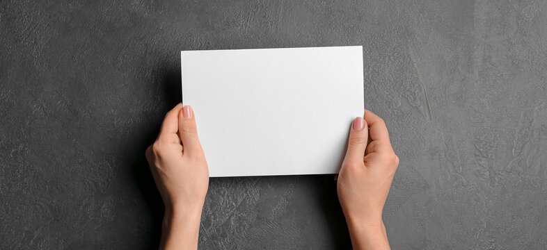 Hands with blank brochure on dark background