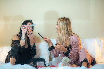 adorable diverse lgbt female couple in bodysuit lying in bed on cream sheets chating after sleeping
