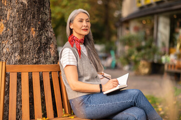 Pretty inspired woman sitting on a bench in the park
