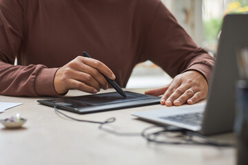 Close up of unrecognizable female artist using graphic tablet and creating new designs