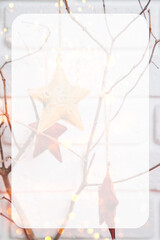 Fototapeta na wymiar Christmas background with place for text. Toys in the form of stars on dry tree branches in lights against a white brick wall. Front view