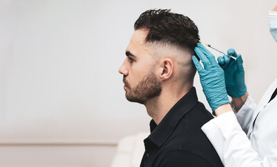 young man receiving hair treatment in a beauty salon. Man having mesotherapy session in aesthetic clinic, therapist hands in gloves making scalp injection,PRP,copyspace.