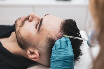 Detail of a young man receiving hair treatment in a beauty salon. Man having mesotherapy session in...