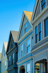 Wood slatted homes with brown and blue and beige pannels and sunlit tiled roofs with clear blue sky and visible windows