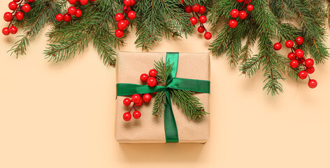 Fototapeta na wymiar Christmas gift box with fir branches and rowan berries on beige background