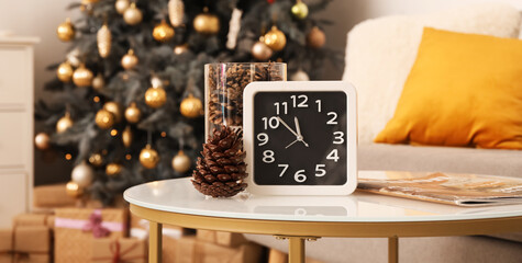 Clock with coniferous cones on table in living room. New Year celebration