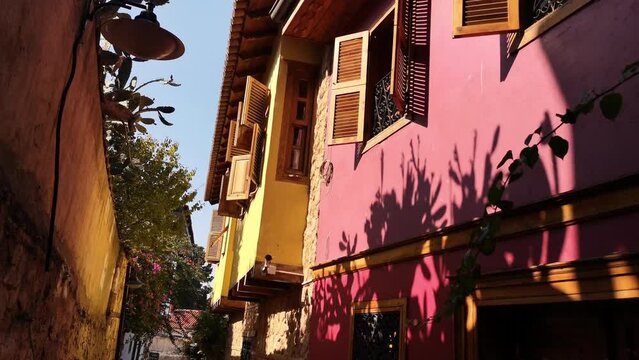 A small turtle dove flies among the old houses with pink walls and wooden shutters in the Old Town of Antalya, Turkey. Video 9 seconds. Narrow Turkish street with ancient historical buildings