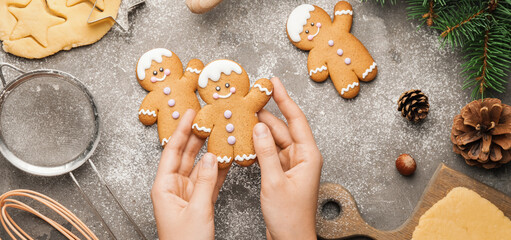 Woman holding Christmas cookie at grey table, top view